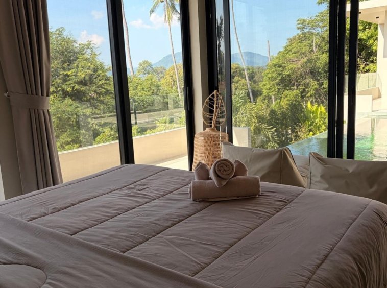 Chambre villa Hua Thanon Koh Samui, lit double vue piscine et palmiers par baies vitrées panoramiques