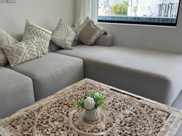 Canapé d'angle gris coussins bohème table basse bois sculpté appartement Emerald Samui
