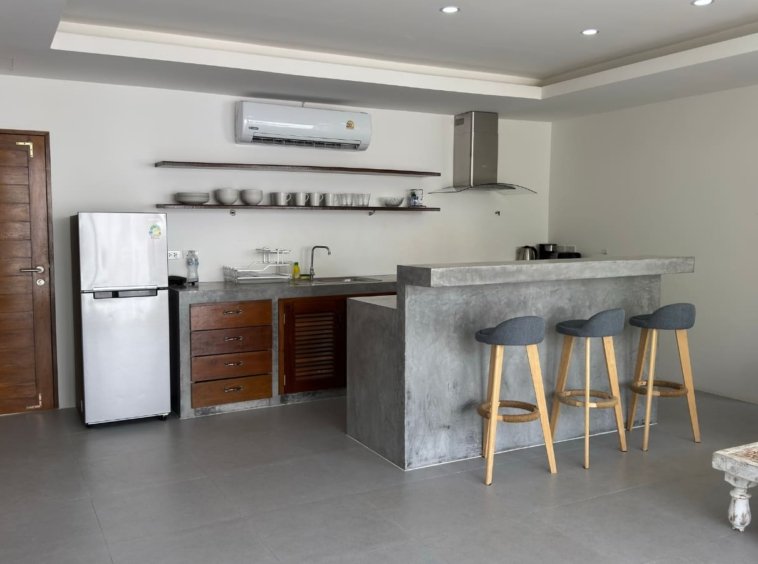 Cuisine équipée béton ciré meuble teck réfrigérateur hotte bar appartement Emerald