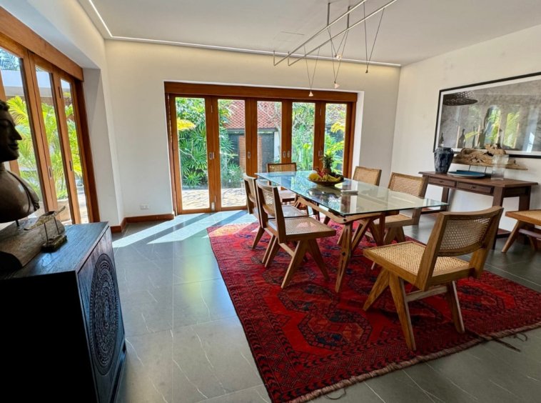 Salle à manger intérieure table en verre chaises rotin tapis persan buste Bouddha