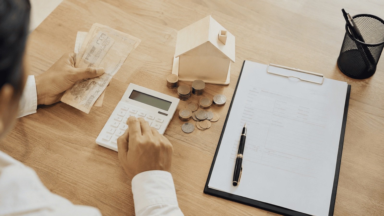 Calcul de la taxe foncière thaïlandaise avec billets, pièces, maison miniature en bois et avis d'imposition