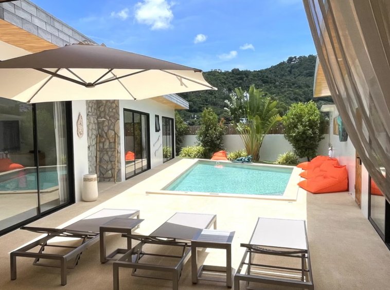 Terrasse avec transats et parasol de la Villa Yolo, vue sur la montagne