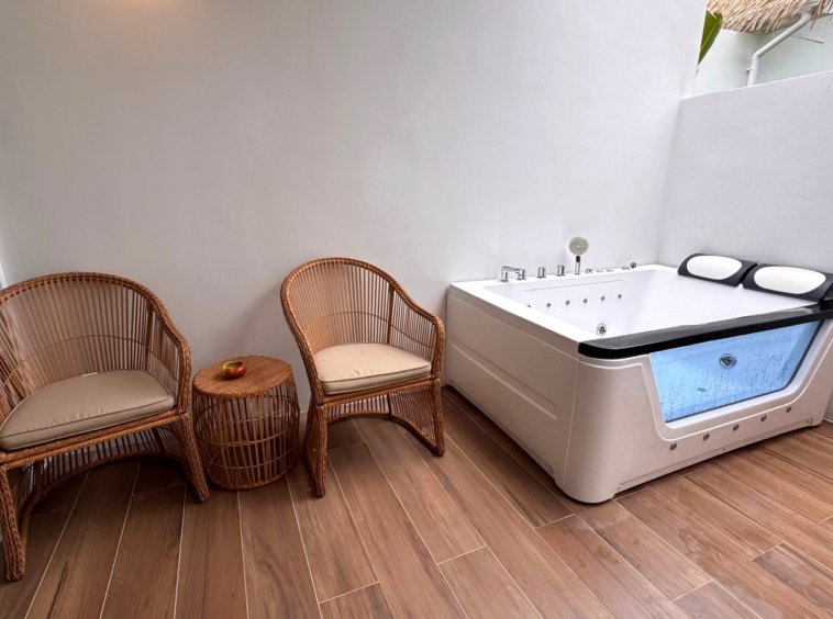 Terrasse fermée avec salon en rotin et baignoire balnéo