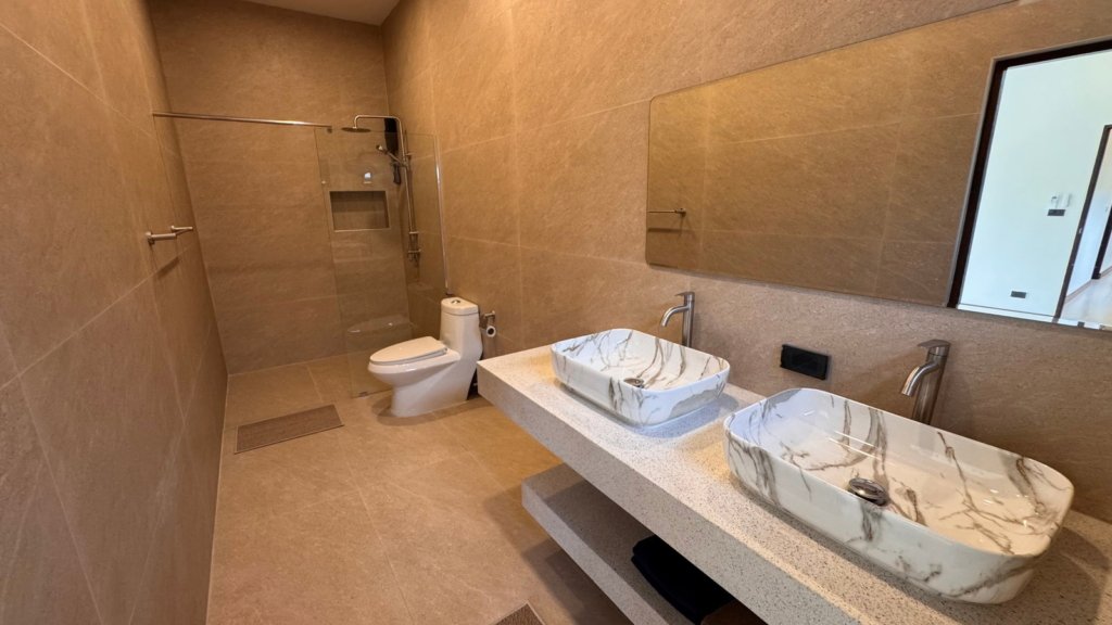 Salle de bain avec double vasque et douche à l'italienne d'une villa du projet Chana Village